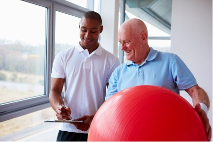 A man wearing a white shirt and another man wearing a light blue polo and holding a red ball